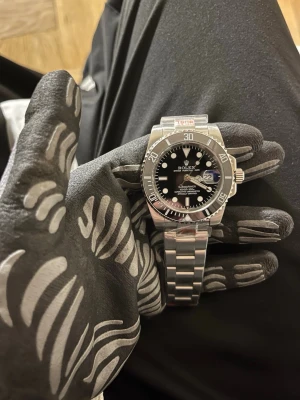 Herrklocka Submariner Date - Modell: Submariner Date • Referens: 116610LN (”Submariner Date Black”) • Diameter: 40 mm • Material: Oystersteel (rostfritt stål) • Urverk: Automatiskt  • Vattentäthet: 300 meter / 1000 ft • Glas: Safirglas med datumförstorare (Cyclops) • Bezel: Svart keramisk (Cerachrom), enkelriktad • Länk: Oyster-länk med säkerhetslås (Glidelock) (med box, certifikat mm 1500kr)