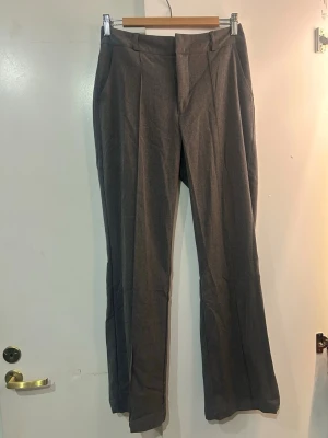 Grå kostymbyxor från Madlady - Snygga grå kostymbyxor från Madlady i rak modell med pressveck och medel hög midja. Byxorna är i ett mjukare material med lite stretch.🌟