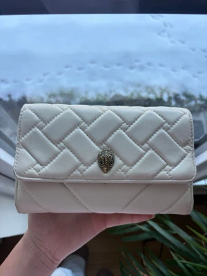 Kurt Geiger väska - Så fin cremevit Kurt Geiger kuvertväska med avtagbart och justerbart guldigt kedjeband. Den är i läder. Små tecken på användning finns men i väldigt bra skick. Köpt för 1900kr🤍