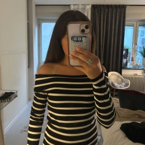Svartvit randig offshoulder tröja - Snygg svartvit randig tröja med offshoulder-design och långa ärmar. Aldrig använd, prislapp kvar. Storlek M men passar även S 🥰🥰