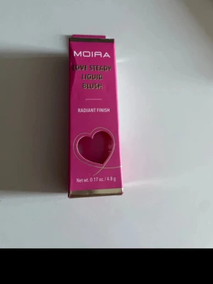 Moira Love Steady Liquid Blush 05 - Moira Love Steady Liquid Blush i nyansen 05 So Cute. Flytande rouge med radiant finish, kommer i en rosa förpackning med hjärtformad detalj. Innehåller 4,8 g och ger en fräsch och glowig look till kinderna.