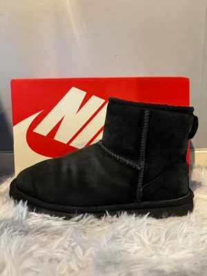 Svarta UGG Classic Mini boots 41 - Ett par svarta UGG Classic Mini boots i mocka med låg skaft och mjuk, fluffig insida. Storlek 41 och i bra skick. Självklart öppen för prisförslag.
