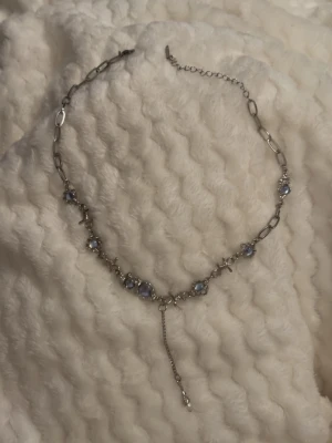 Silverfärgat halsband med blå pärlor -  halsband i silverfärg med blå lristall pärlor och flera detaljer . 
