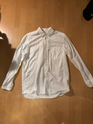 Vit skjorta These Glory Days - Klassisk vit skjorta från These Glory Days i storlek S. Skjortan har lång ärm, bröstficka och knappar framtill. Tillverkad i mjuk bomull och har en clean, tidlös look som passar till många olika stilar.