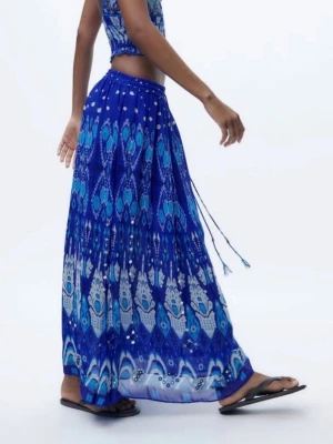 Blå långkjol med mönster och snörning - Säljer en blå långkjol med coolt mönster i olika blå toner och vita detaljer. Kjolen har snörning i midjan och ett flowy fall, perfekt för sommarens alla äventyr. Materialet känns lätt och luftigt.