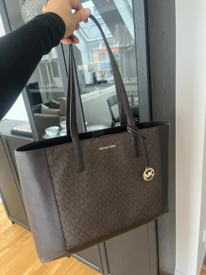 Brun Michael Kors handväska - Handväska från Michael Kors, aldrig använd då jag fick den av mitt ex & inte riktigt är min stil 🥹🥲 pris är diskuterbart då jag gärna säljer den snabbt 🫶🏽