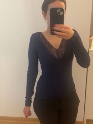 Marinblå tröja med spetsdetalj - Snygg marinblå långärmad tröja med v-ringning och dekorativ spets längs halsen. Har använt den knapp 💗