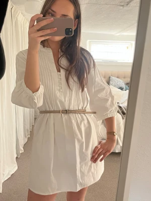Studentklänning  - Säljer denna så fina vita klänning, perfekt till studenten. Står storlek 40 i, tror att det är en tunika egentligen men den sitter bra på mig som bär S och är ca 173 cm.  Observera att skärpet inte ingår, visar i sista bilderna hur den ser ut utan skärp. 🩷