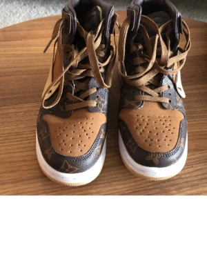 Bruna höga sneakers - Unika sneakers i brunt och beige med klassiskt mönster och detaljer. Högt skaft, vita sulor och bruna skosnören. textdetaljer på sulan. Perfekta för dig som vill sticka ut med lyxig streetstyle.