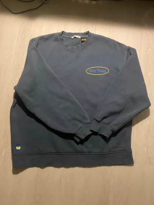 Wu-Tang marinblå sweatshirt - Cool svart sweatshirt från Zara med gul och blå logga på bröstet och stort tryck på ryggen med texten 'Wu-Tang Forever'. Tröjan har rund hals, långa ärmar och ribbade muddar. Perfekt för dig som gillar streetwear och hiphop.