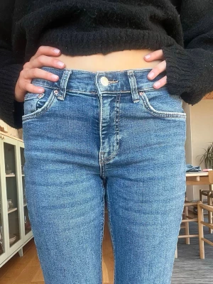 Blå skinny jeans med hög midja - Säljer ett par klassiska blå bootcut jeans med medelhög midja och fickor. Jeansen har en snygg tvätt och en passform som sitter tight. Perfekta till en stickad tröja eller crop top. Materialet är stretchigt denim för extra komfort.