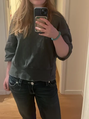 Mörkgrå croppad hoodie - Säljer en mörkgrå croppad hoodie med breda muddar och avslappnad passform. Tröjan har korta ärmar och pr mörkgrå. Perfekt för dig som gillar en chill och trendig look.