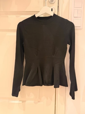 Svart långärmad topp Gina Tricot - Säljer en svart långärmad topp från Gina Tricot med rund halsringning och figurnära passform. Toppen har markerad midja och lätt utsvängd nederdel som ger en snygg siluett. Perfekt att styla med jeans eller kjol. Tröjan har använts en gång💖