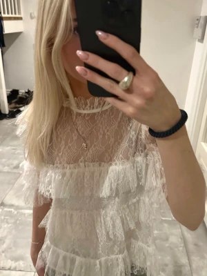 By Malina Birger Blus - Superfin vit blus i spets med flera lager volanger och korta ärmar. Är 162 cm lång och använd ca 2 gånger. Tänk köpa en annan färg därmed säljer jag denna💕💕