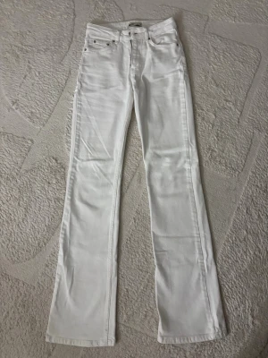 Vita flare jeans med hög midja - Säljer ett par vita flare jeans med hög midja. Klassisk femficksmodell med bälteshällor och dragkedja. Snygga att styla med sneakers eller boots för en clean look.