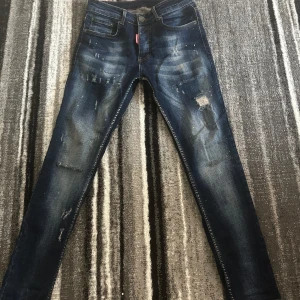 Blå jeans från DSQUARED2 - Snygga blå jeans från DSQUARED2 med slitna detaljer och en tight passform. De har en klassisk femficksdesign och en diskret logga på baksidan. Perfekta för en trendig look.