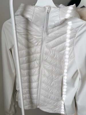 Vit dunjacka med huva - Vit figursydd dunjacka med luva. Jätte fin till våren och sommaren. Inget slitage på jackan och sparsamt använd, (tvättas även innan den postas) Stl 36 men skulle säga att den passar S, XS i storlek med. Från stadium