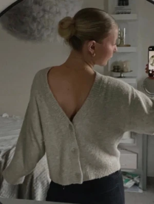 Beige stickad kofta med djup v-ringning  - Säljer en beige stickad kofta med v-ringning och knappar framtill. Den har fortfaranade ett mjukt material och har används varsamt 
