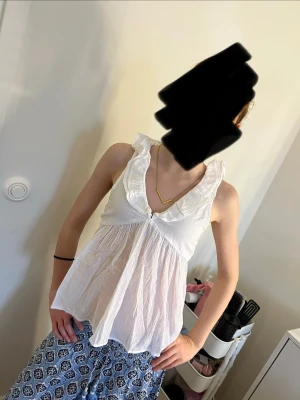 Vit volang topp med knyt i ryggen - Söt vit topp med volangkant och djup v-ringning. Luftigt material som passar perfekt till sommaren. Så fin o enkel att matcha med olika outfits.