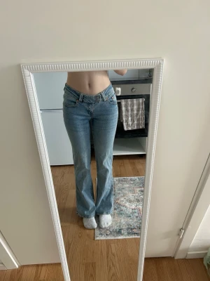 Ljusblå bootcut jeans med brodyr - Säljer ett par ljusblå bootcut jeans med låg midja och snygg broderad detalj på bakfickan. Jeansen har klassisk femficksdesign och är i ett mjukt denimtyg. Perfekta för dig som gillar en retro vibe och vill ha något som sticker ut lite extra.