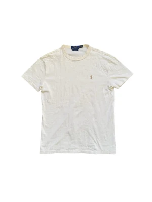t-shirt från Polo Ralph Lauren - Storlek xs men sitter som s Klassisk beige t-shirt från Polo Ralph Lauren med rund halsringning och broderad logga på bröstet. Tillverkad i mjuk bomull och har en normal passform. Perfekt för en clean och stilren look.