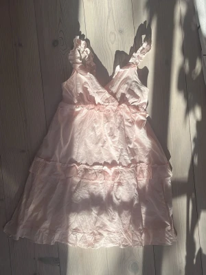 Ljusrosa volangklänning med axelband - Söt ljusrosa klänning med volangdetaljer och smala axelband. använde på skolavslutningeb förra året och har inte kommit till användning sen dess men super fin verkligen❣️❣️ köpt från kids brand store och är u storlek 158-164 cm men passar mig som har S då den är stretchig❣️❣️