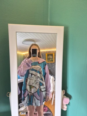Pastellfärgad oversized t-shirt med tryck - Cool oversized t-shirt i pastellfärger med ett stort, unikt grafiskt tryck framtill. T-shirten har långa ärmar och en loose passform, perfekt för dig som gillar streetwear och statement-plagg. Materialet känns mjukt och bekvämt mot huden.