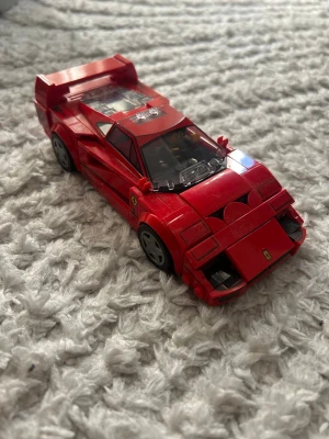 Röd LEGO Ferrari F40 bil - Säljer en röd LEGO-bil som föreställer en Ferrari F40. Bilen har sportig design med tydliga detaljer som bakspoiler, svarta fälgar och genomskinliga rutor. Perfekt för dig som gillar bilar och LEGO! 🚗