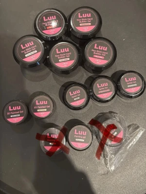 Luu gelé- och spindelgeler för naglar - Flera burkar Luu geléprodukter för naglar, inklusive Non Stick Hard Builder Gel, 3D Painted Gel, Spider Gel och Painting Gel. Förpackningarna är svarta med rosa etiketter. Perfekt för kreativa nageldesigner och konstnärliga effekter.