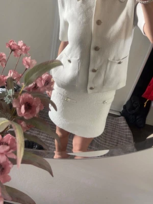 Vita  shorts med knappar - Snygga vita shorts i ett fluffigt material med två dekorativa silverfärgade knappar framtill. Shortsen har en stilren och modern look, perfekta för att lyfta din outfit.