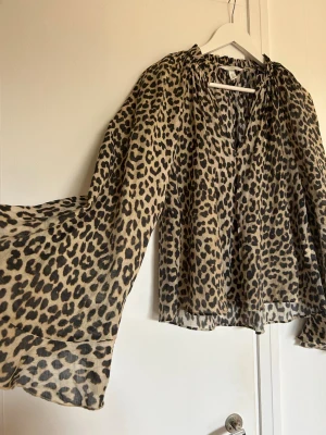 Leopardmönstrad blus från H&M - Snygg och luftig blus från H&M med leopardmönster i beige och svart. Blusen har vida, långa ärmar 