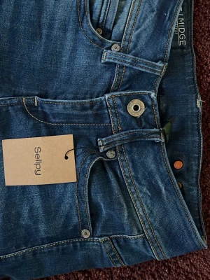 Blå bootcut jeans från G-Star RAW - Snygga blå bootcut jeans från G-Star RAW, modell Midge. Jeansen har klassisk femficksdesign, kontrastsömmar och en lätt tvättad look. Perfekta för dig som gillar en avslappnad men trendig stil.