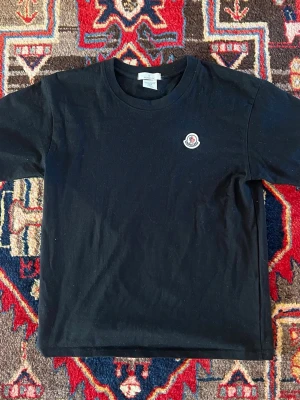 Svart Moncler t-shirt i - Säljer en svart t-shirt från Moncler, endast använd få gånger och är i perfekt skick. Köpt i butik för runt en månad sedan