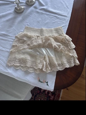 Spetsshorts - Superfina beige virkade shorts med flera lager volanger. De har en elastisk midja och är perfekta för varma dagar.