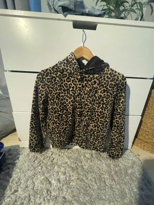 Leopardmönstrad hoodie - Säljer en fluffig hoodie med leopardmönster. Tröjan är brun och svart, har en ficka framtill och är tillverkad i mjukt, mysigt material. Jättevarm och skön. Väldigt stretchig och skön.