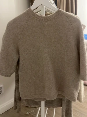 Beige stickad tröja  - Beige stickad tröja från & Other Stories  med korta ärmar. Tröjan är lite nopprig men annars väldigt fin och stilren.