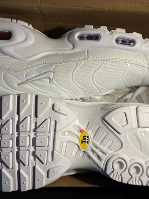 Nike Air Max Plus vita sneakers - Nike Air Max Plus sneakers i helvitt med ikoniska vågformade detaljer och synliga Air Max-enheter i sulan. Ovandel i mesh och syntet, med tydlig Swoosh-logga på sidan. Sulan har TN-logga undertill och ger en sportig vibe.
