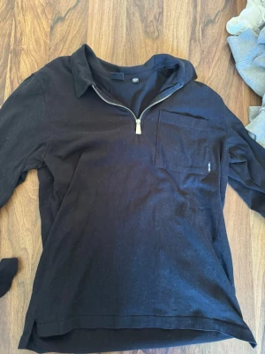 Svart halvzip-tröja Only & Sons - Svart långärmad tröja från Only & Sons med halv dragkedja och bröstficka. Tröjan har klassisk krage och är tillverkad i mjukt material, perfekt för en avslappnad stil.