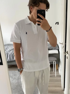 Ralph Lauren piké - Säljer en stilren vit pikétröja från Ralph Lauren i storlek M. Tröjan är sparsamt använd och i mycket fint skick – inga fläckar, hål eller andra defekter.  Klassisk modell med krage och knappar framtill samt den ikoniska loggan på bröstet. Perfekt både till vardags och lite mer uppklädda tillfällen.  Passar dig som är cirka 175–185 cm beroende på önskad passform.  Hör av dig vid intresse!