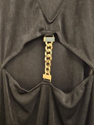 Svart klänning med guldkedja Boohoo - Snygg svart klänning från Boohoo med djup v-ringning och öppen midja som hålls ihop av en chunky guldfärgad kedjedetalj framtill. Ärmlös modell i mjukt material, perfekt för dig som vill sticka ut.