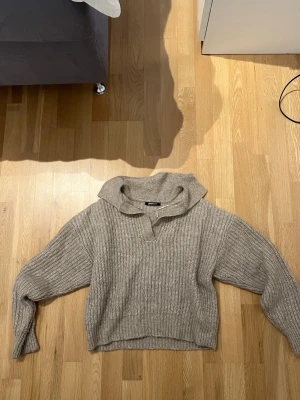 Beige stickad tröja från Gina Tricot - Mysig beige stickad tröja från Gina Tricot med krage och v-ringning. Tröjan har en avslappnad passform, ribbstickat mönster och långa ärmar.  Använd fåtal gånger. ❤️