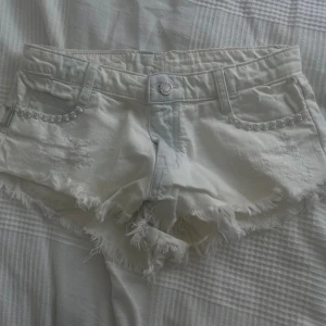 Zadig & Voltaire shorts - Säljer ett par vita lågmidjade jeansshorts från Zadig Voltaire med dödskalle detaljer vid fickorna, supercoola och unika!