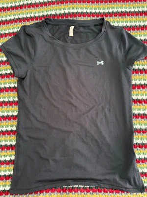 Tränings T-shirt från UnderArmour - Säljer en svart tränings T-shirt från UnderArmour i storlek S🙌 Använd en del men fortfarande i superbra skick.  Svarar gärna på frågor!💗