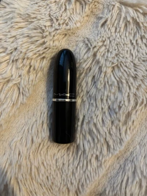 MAC Lustreglass Lipstick Syrup - MAC Lustreglass Lipstick i nyansen Syrup, ett läppstift med glansig finish. Hylsan är svart med silverdetalj och klassisk MAC-logga. Läppstiftet har en smidig, rundad form och är tillverkat i plast.