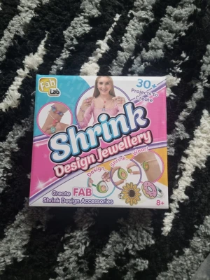 Shrink Design Jewellery kit - Roligt och kreativt kit från FabLab för att designa och skapa egna smycken med krympplast. Innehåller material för att göra armband, halsband och nyckelringar med färgglada motiv. Passar för dig som gillar att pyssla och skapa unika accessoarer.