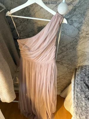 Ljusrosa balklänning - Säljer nu min balklänning från nian. Superfin rosa one shoulder klänning med slits. Står ingen storlek men har för mig att det är 34/36. Hör bara av dig vid frågor så svarar jag snabbt. Den är använd en gång men jag glömde ta av lappen. Så ja gick runt hela balen med lappen i, där av är lappen fof kvar🫠🫠🫠