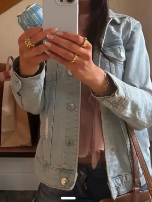 Ljusblå jeansjacka - Trendig ljusblå jeansjacka med slitna detaljer och klassisk krage. Jackan har två bröstfickor med knappar och silverfärgade knappar framtill. Perfekt oversized passform för en avslappnad look. Passar till allt och ger en cool vibe.