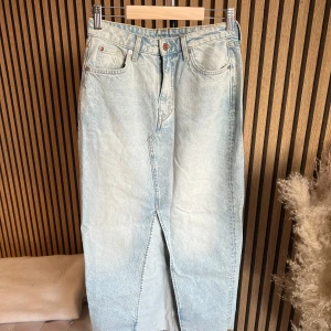 Ljusblå jeanskjol från H&M  - Lång jeanskjol i ljusblå denim från Weekday. Klassisk femficksmodell med hög midja, knapp- och dragkedjestängning samt slits framtill. Perfekt för en avslappnad och trendig look.