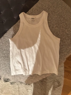 Vit ribbad linnetopp från Aim'n - Säljer en vit ribbad linnetopp från Aim'n i storlek S. Toppen är ärmlös med en croppad passform och tillverkad i mjuk bomull med lite elastan för extra stretch. Perfekt till jeans eller shorts för en clean och enkel look.
