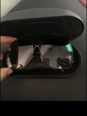 Victoria Beckham pilotbågar solglasögon - Snygga solglasögon från Victoria Beckham med klassisk pilotform. Bågarna är i silverfärgad metall och glasen är tonade i grått. Kommer med ett exklusivt svart fodral med guldfärgad logga. Perfekta för en trendig look i solen.